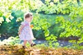 Beautiful baby girl in pink dress walking next to