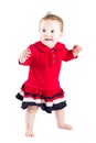 Beautiful baby girl in a red dress making her first steps Royalty Free Stock Photo