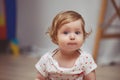 A beautiful baby girl with red hair 10 months plays in the room. The child looks in surprise with big blue Royalty Free Stock Photo