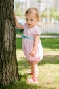 Beautiful baby girl touching a tree