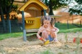 Beautiful baby having fun on sunny warm summer day - Cute toddler girl playing in sand on outdoor playground Royalty Free Stock Photo