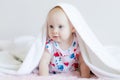 Beautiful baby kid Peeps out from under the sheets and fervently plays posing for the camera Royalty Free Stock Photo