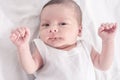 Beautiful baby lying down on white sheets.