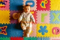 Beautiful baby lying on her back funny playing in her colorful room and protected against bumps Royalty Free Stock Photo