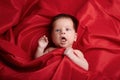 Beautiful baby lying on red silk background Royalty Free Stock Photo