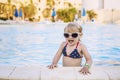 Beautiful baby in the pool happily smiling in sunglasses