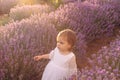 Beautiful babygirl in a white dress walking with a bouquet in a lavender field. Sunset view. Summer scenic view. Portrait of Royalty Free Stock Photo