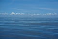 Beautiful background scene of gradient blue sky and low raining white cloud above deep blue sea moving water ripple Royalty Free Stock Photo