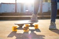 beautiful backlit photo of a cruiser skateboard held by the feet of a young girl in the park Royalty Free Stock Photo