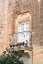 Beautiful balcony with flower pots and French doors in Mdina, Malta.