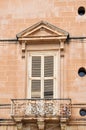 Beautiful balcony with French doors on the facade of an ancient stone house. Photo taken in Mdina, Malta.