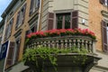Beautiful balcony with windows and flowers. Orange brick building facade with windows, and shutters in downtown