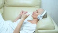 Beautiful bald girl in headphones enjoys music at home on the couch