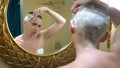 Beautiful bald woman looks in a luxurious bathroom mirror and does her hair, shaves her hair with a dangerous razor