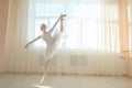 Beautiful ballerina in body and white tutu is training in a dance class. Young flexible dancer posing in pointe shoes.