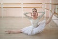 Beautiful ballerina in body and white tutu is training in a dance class. Young flexible dancer posing in pointe shoes