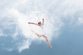 Beautiful ballet dancer jumping inside cloud of powder