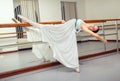 Beautiful ballet dancer in white tutu posing on one leg next to handle bar. Royalty Free Stock Photo