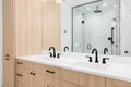 A beautiful bathroom with wood cabinet, white countertop, and marble shower. Royalty Free Stock Photo
