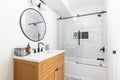A bathroom with a wood cabinet and marble subway tile shower. Royalty Free Stock Photo