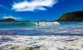 Beautiful bay with big waves, unrecognizable surfer, blue sunny sky - Pataua, New Zealand