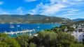 Beautiful bay with blue water and marina with boats. Small town and green mountains