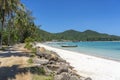 Beautiful bay with dirt road, blue sea water, coconut palm trees and boats. Tropical sand beach and sea water on island Koh Royalty Free Stock Photo