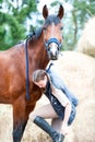 Beautiful bay horse looking in to camera standing near girl Royalty Free Stock Photo