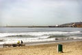 A beautiful beach in Ensenada with the port in the background and people enjoying the seashore. Royalty Free Stock Photo