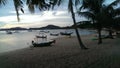 Beautiful beach with Palm trees, tranquil bay with traditional fisherman boats at sunset. Silhouette of the objects. Royalty Free Stock Photo