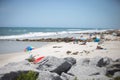 Beach scene in Florida with jetty rocks and tourists and large umbrellas and sunbathers