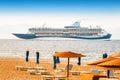 beach with sunbeds and huge cruise ship at the background Royalty Free Stock Photo