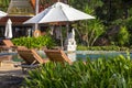 Beautiful beach with swimming pool, palm trees, daybeds and umbrella in a tropical garden near sea