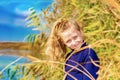 A beautiful, beautiful and young girl in a blue sweater is smiling in the reeds on the bank of the river, her hair backlit by the Royalty Free Stock Photo