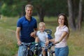 Beautiful bicyclist family, leisure in pine forest, happy parents.