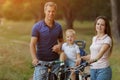 Beautiful bicyclist family, leisure in pine forest, happy parents.