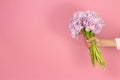 Beautiful big bouquet of double violet tulip flowers in hand on pastel pink background