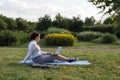 Beautiful big woman lying on the green grass in park with her laptop and working. Student girl looking at the computer screen Royalty Free Stock Photo