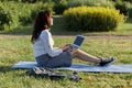 Beautiful big woman lying on the green grass in park with her laptop and working. Student girl looking at the computer screen Royalty Free Stock Photo