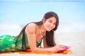 Beautiful biracial teen girl lying on tropical beach with phone Royalty Free Stock Photo