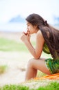 Beautiful biracial teen girl sitting at tropical beach, praying