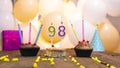 A beautiful birthday card for a woman with the number 98 in a cupcake against the background of balloons. Happy birthda