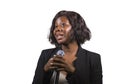 Beautiful black afro American business woman with microphone speaking in auditorium at corporate event or seminar giving Royalty Free Stock Photo