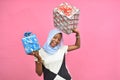 beautiful black girl holding gift boxes and presents smiling and feeling excited, in front of pink background Royalty Free Stock Photo