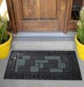 Beautiful Black Grey Bobblestone Welcome Entry Rubber Glitter door mat with yellow flowers and leaves Royalty Free Stock Photo