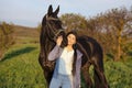 Beautiful black horse  with his owner and rider  posing in green grass meadow. spring time Royalty Free Stock Photo