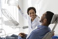 Beautiful black lady dentist greeting male patient on her workplace