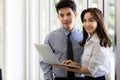 Beautiful black long hair Asian businesswoman standing watching the screen of laptop notebook computer and talking with Royalty Free Stock Photo