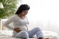 Beautiful black pregnant woman hugging tummy while relaxing on bed at home Royalty Free Stock Photo