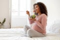 Beautiful black pregnant woman with radiant smile eating fresh vegetable salad Royalty Free Stock Photo